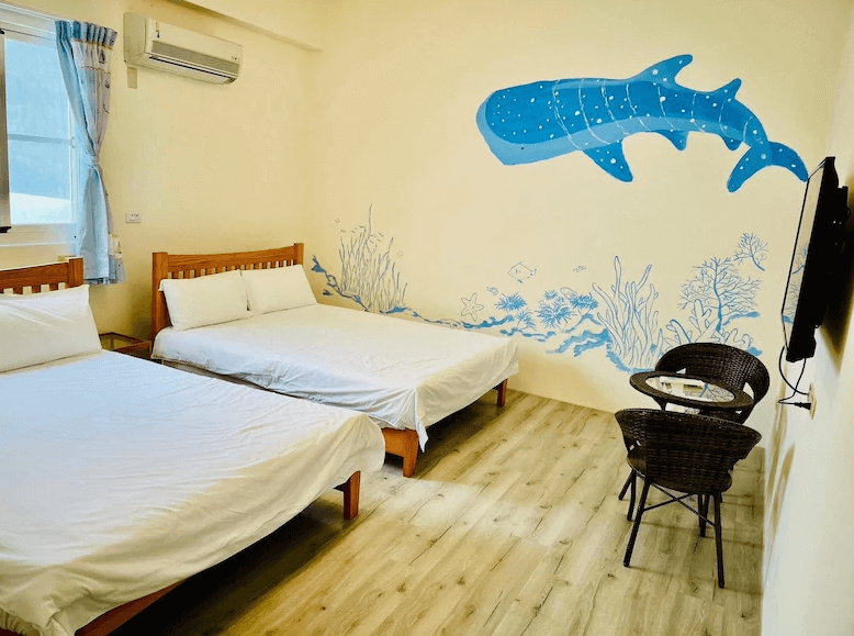 【綠島住宿】綠島藍漾海墅的房內牆面彩繪可愛鯨鯊與海底世界，搭配木質床架與兩張雙人床，營造出童趣與海洋氣息並存的住宿體驗，適合親子家庭入住。