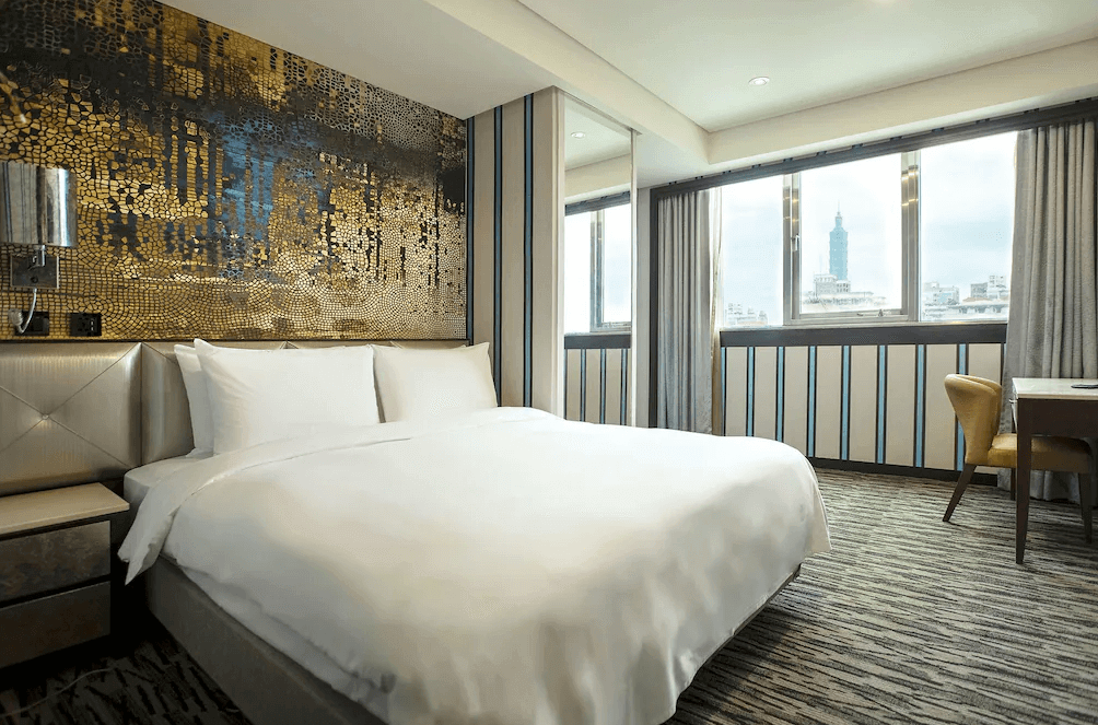 【台北小巨蛋住宿】艾捷天麗大飯店的奢華風格雙人房，搭配金色馬賽克藝術牆面與大片窗景，可遠眺台北101地標景觀，空間典雅舒適。