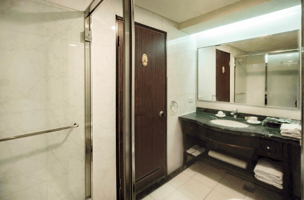 【台北小巨蛋住宿】艾捷天麗大飯店的大理石浴室，配有寬敞洗手台與乾濕分離淋浴空間，簡潔實用並提供多項備品與毛巾。