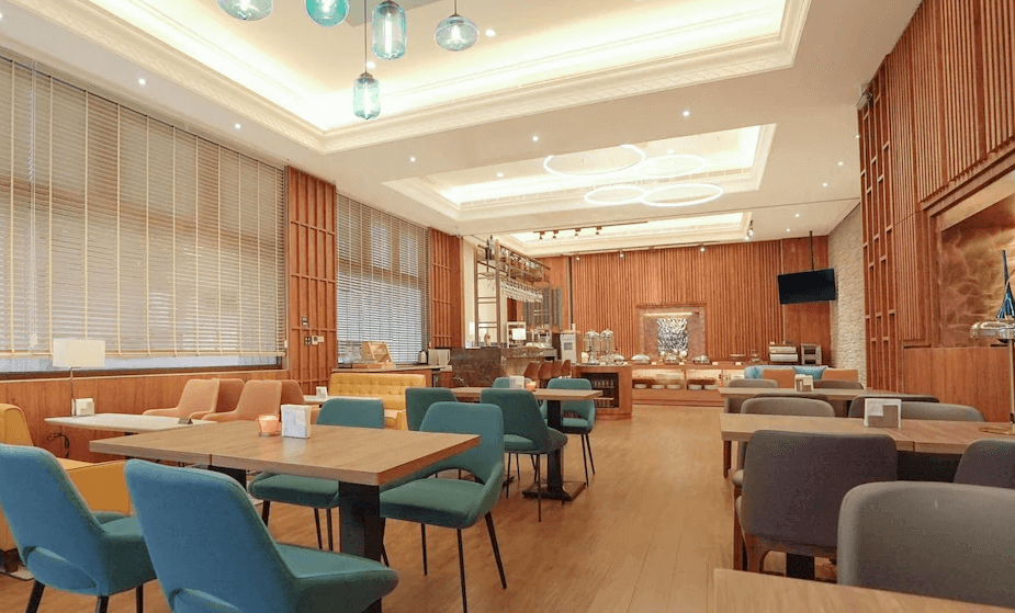 【台北小巨蛋住宿】艾捷天麗大飯店的自助餐廳，設有多款色彩柔和的座椅與溫潤木質牆面，環境寬敞明亮，提供舒適用餐體驗。