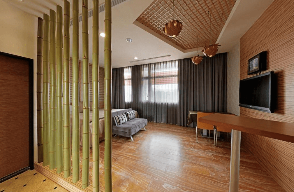 【草屯住宿】草屯知達工藝會館的房型，空間以木地板與木紋牆面為主，竹子隔間巧妙區分臥室與起居空間，搭配藤編吊燈與格柵天花設計，呈現濃厚的東方禪意氛圍。