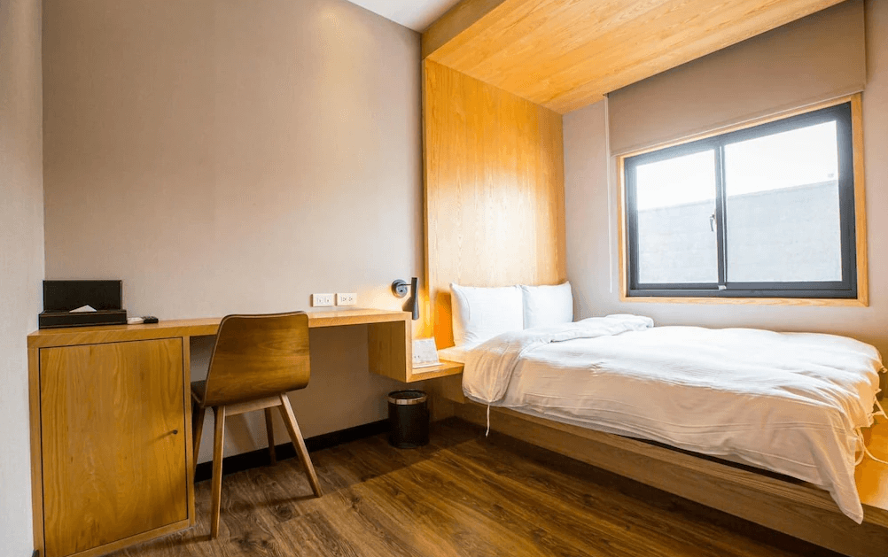 【一中街住宿】葉綠宿一中館的單人房空間，配有一張單人床與書桌，木質家具與床頭牆面相呼應，自然採光良好，是一人旅客或商務入住的理想選擇。