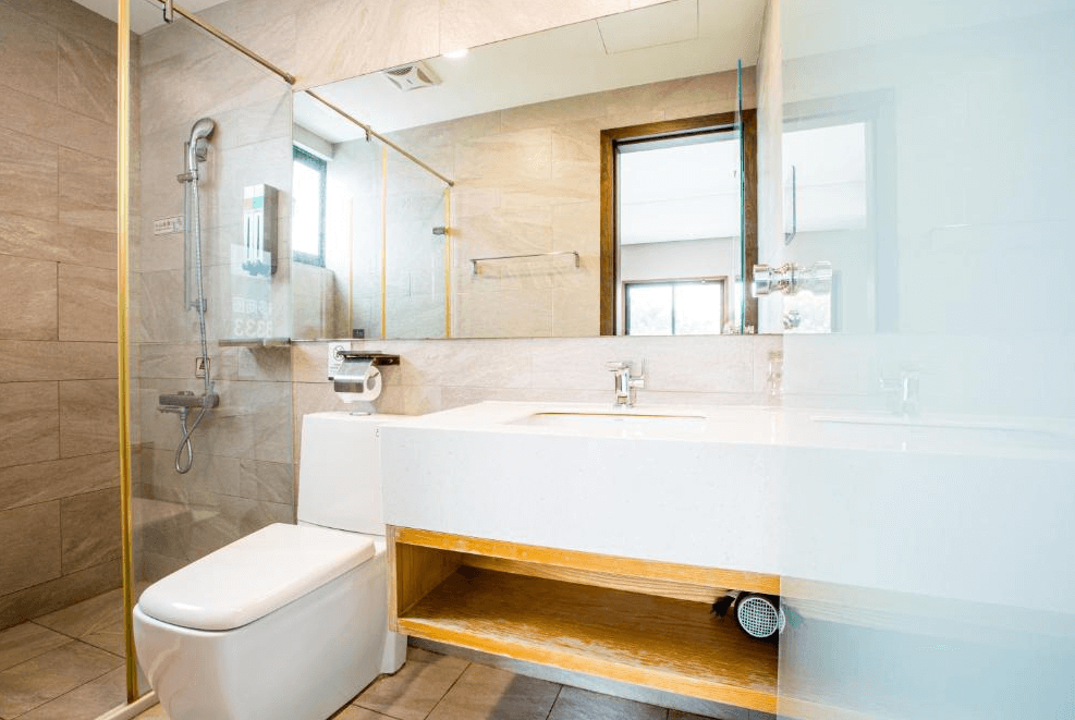 【一中街住宿】葉綠宿一中館的浴室，設有乾濕分離淋浴間與大片鏡面，洗手台下方設有置物空間，牆面為淺色石紋磁磚，整體明亮潔淨。