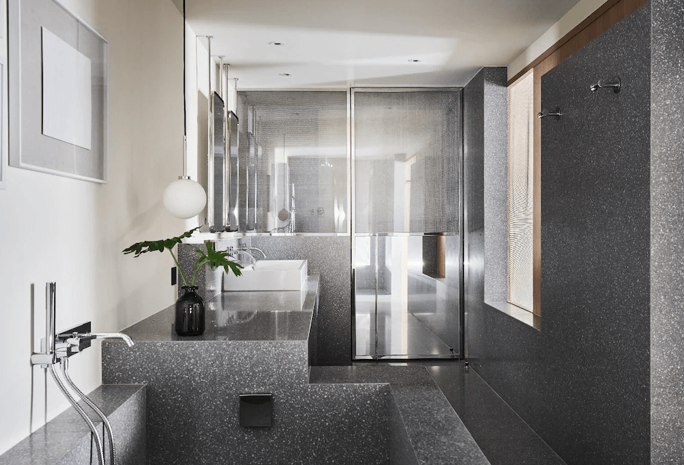 【台北寵物友善住宿】金普頓大安酒店的浴室設計以灰色石紋為主體，搭配玻璃淋浴間與嵌入式浴缸，設有現代吊燈與雙洗手台，空間質感沉穩，細節講究。