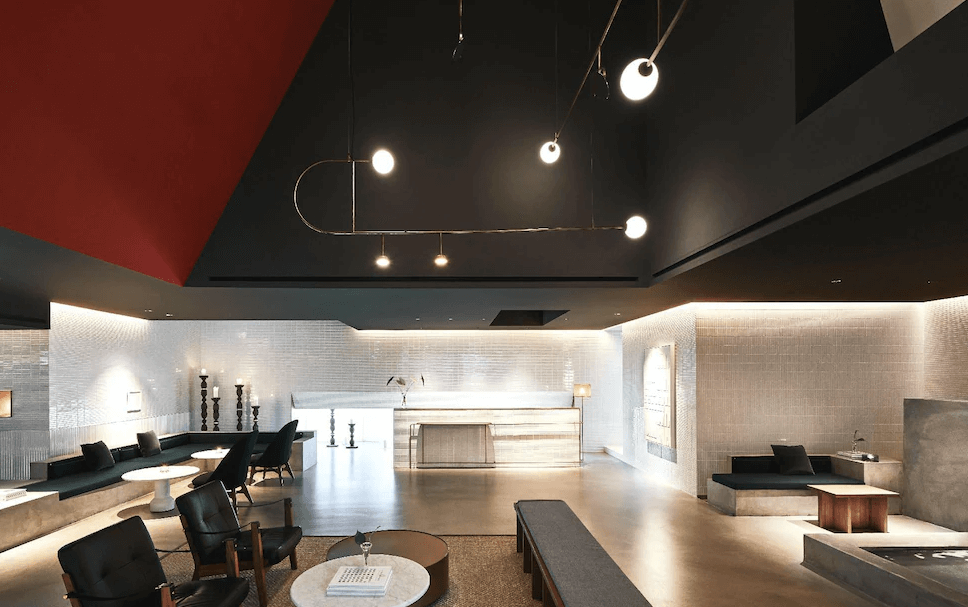 【台北寵物友善住宿】金普頓大安酒店的大廳空間融合現代與藝術風格，挑高黑色天花搭配藝術吊燈，設有沙發區與多組座椅，牆面以白色磁磚與柔和燈光營造溫馨質感氛圍。