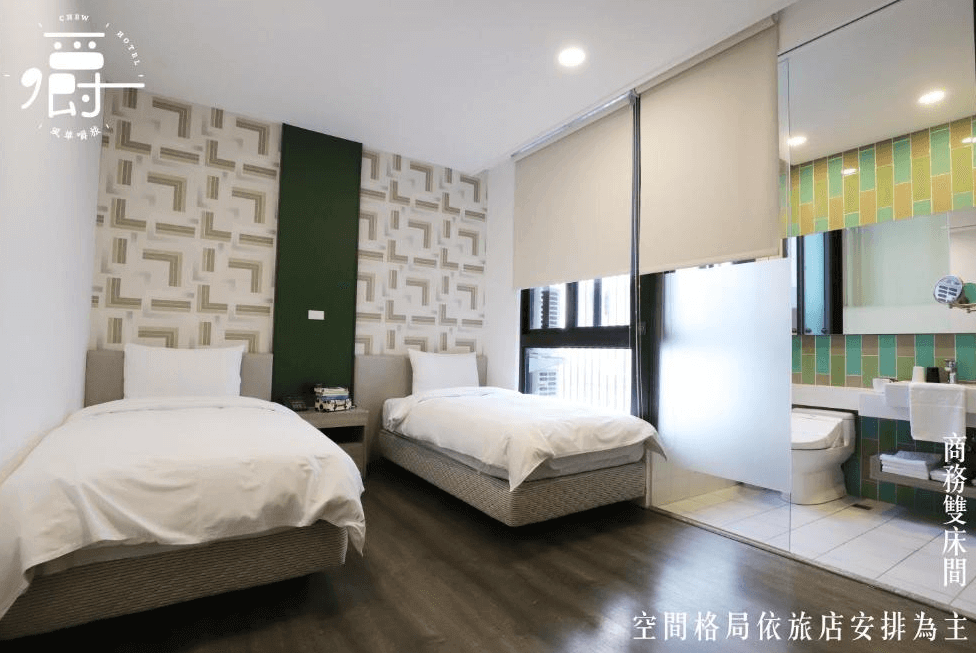 【一中街住宿】風華嚼旅的商務雙床房，牆面以米白與綠色跳色幾何圖案裝飾，配有兩張單人床與大片對外窗，浴室採用綠黃拼色磁磚，整體空間清新舒適。