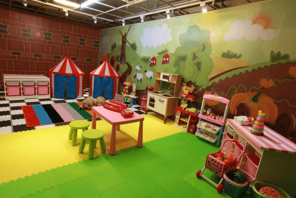 【楊梅住宿】麗多森林溫泉酒店的親子遊戲室，設有兒童帳篷、小廚房玩具、購物推車與豐富教具，地面鋪設柔軟的彩色拼接地墊，牆面為可愛童趣的農場主題插畫，是孩子放電遊玩的好地方。