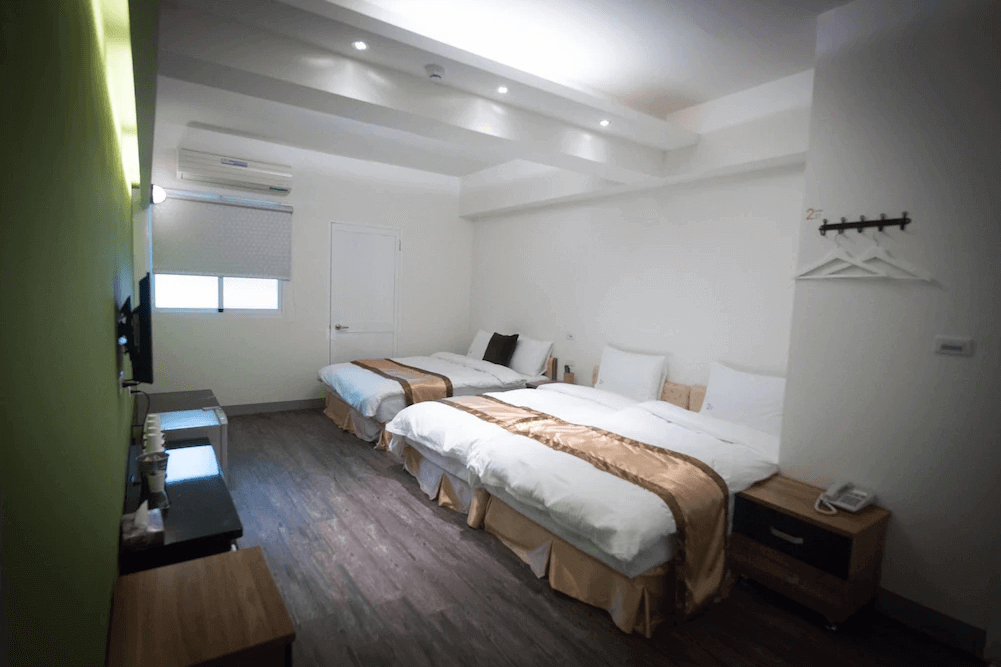 【高雄寵物友善住宿】237重機主題旅店的房內配置兩張大床與一張單人床，可容納三至四人入住，設計簡潔明亮，牆面為白色與綠色搭配，地板為深色木質風格，適合家庭或朋友同行入住。