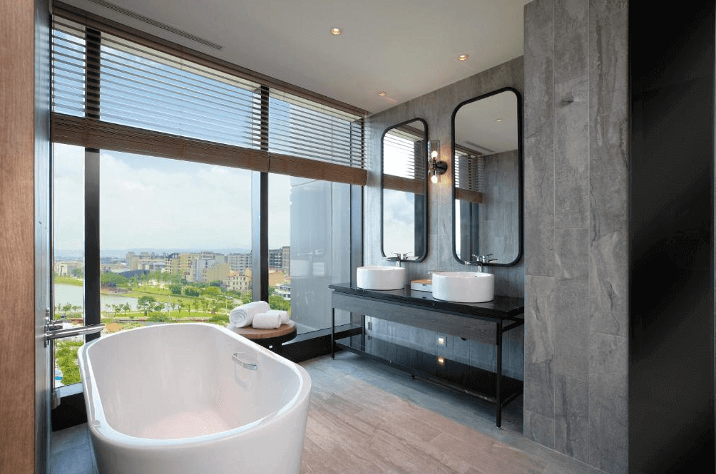 【桃園機場住宿】“Xpark住宿”COZZI Blu 和逸飯店 桃園館的高級浴室設計，設有獨立浴缸與雙洗手台，大片玻璃窗可眺望園區綠意與城市風光。