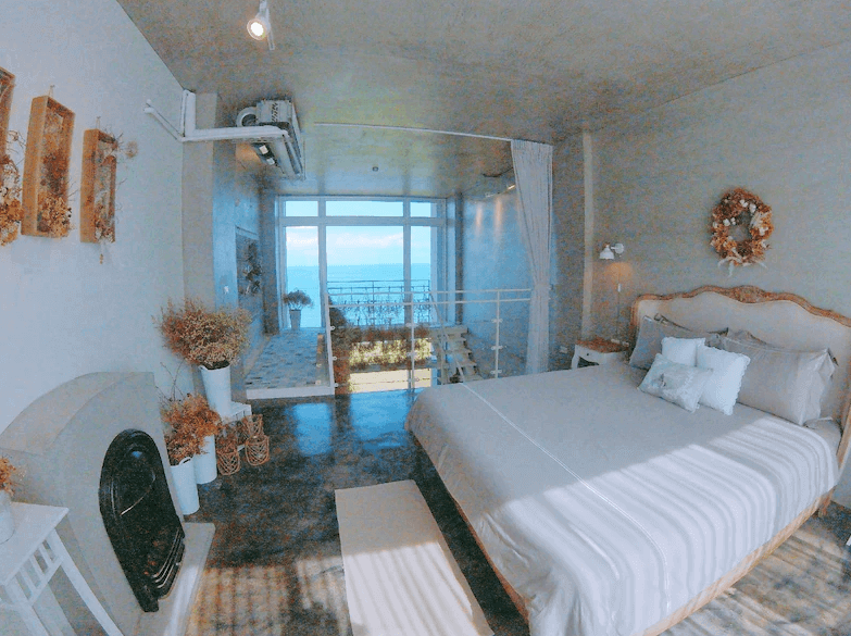 【豐濱住宿】Noosa 海岸行館的海景雙人房，整體以溫柔白色與米色為主調，搭配乾燥花與鄉村風裝飾，大片落地窗可眺望蔚藍海景，空間明亮舒適，充滿浪漫氛圍。