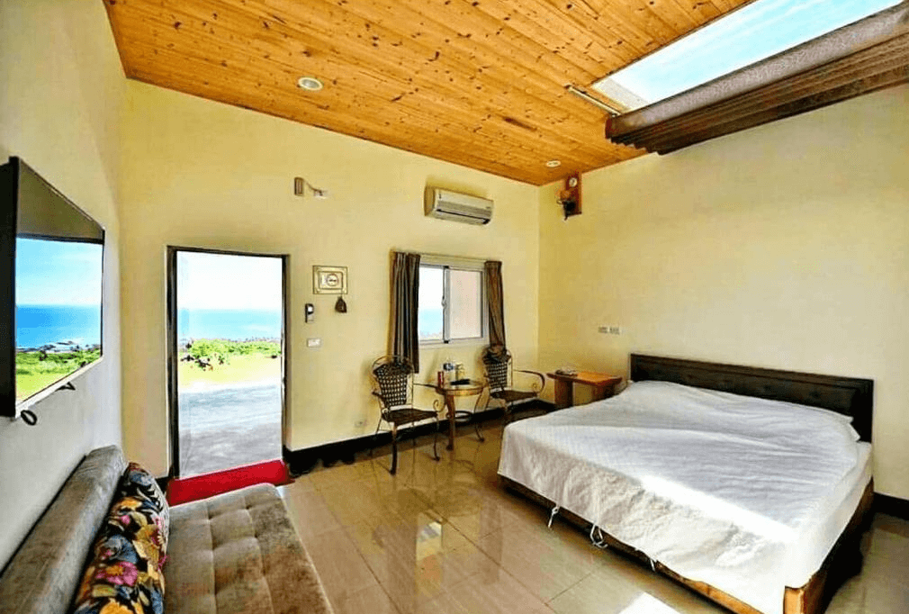【台東成功住宿】台東「三仙台小月光民宿」海景雙人房，房內設有舒適雙人床與沙發座椅，大片窗戶與門外皆可直視海景，搭配木質天花板與天窗設計，空間明亮通透、氛圍放鬆。