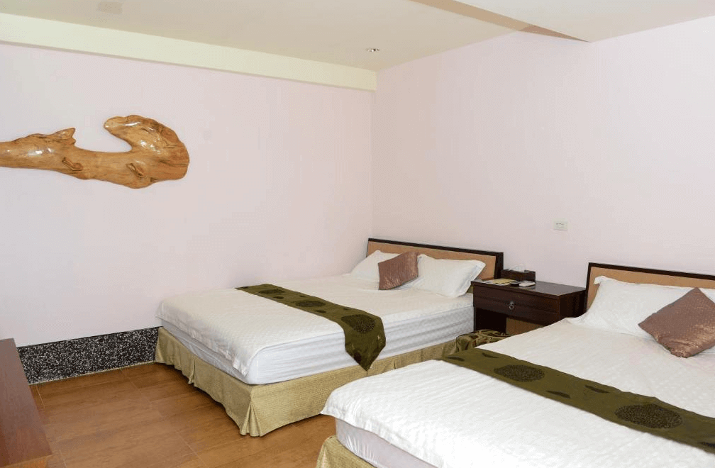 【豐濱住宿】來去海邊玉石咖啡民宿館的雙人雙床房，簡約清爽的設計風格，房內配置兩張舒適雙人床，牆面懸掛原木藝術裝飾，營造溫馨自然的住宿氛圍，適合家庭或好友同行入住。