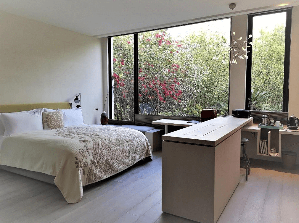 【苗栗包棟民宿】八角隱士莊園，房內設有一張大型雙人床，大片落地窗外即是綠意庭園與盛開花卉，自然採光充足，室內設計簡約優雅，另備有吧檯與泡茶設備，提供舒適療癒的住宿體驗。