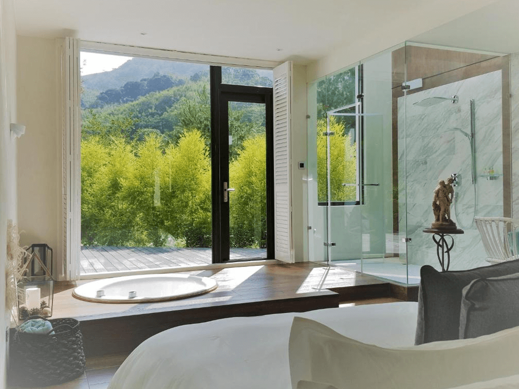 【苗栗包棟民宿】八角隱士莊園，客房設有獨立圓形湯池與玻璃淋浴間，開門即見翠綠山景與大片竹林，享有極佳隱私與自然療癒氛圍，適合情侶或自我放鬆旅行。