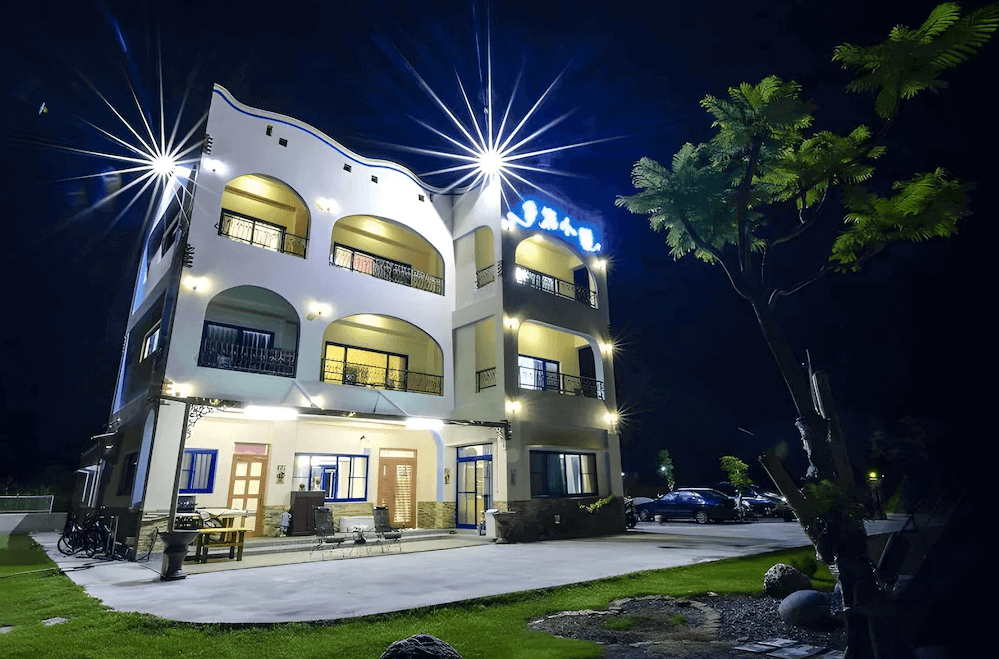 【台東成功住宿】台東「幸福小築民宿」建築外觀夜景，三層樓白色建築搭配圓拱造型陽台，燈光點綴下顯得典雅迷人，戶外空間寬敞，備有座椅與停車區，環境清幽舒適。