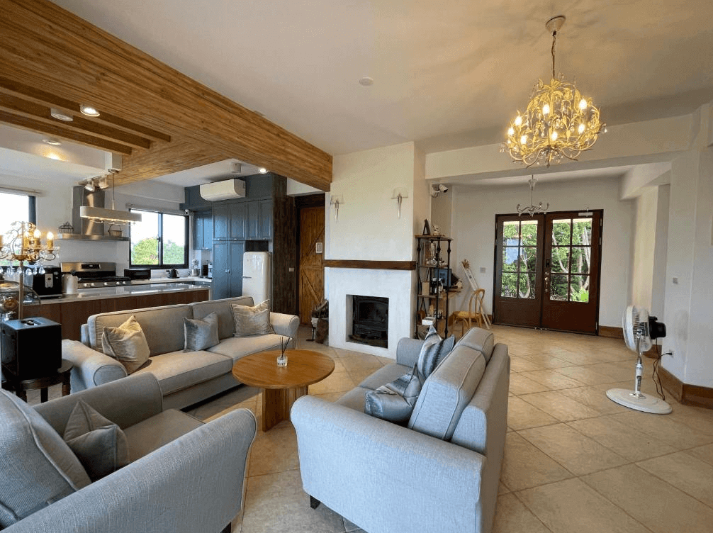 【台東成功住宿】台東海景民宿「奧麗雅安莊園」的公共客廳及廚房空間，設計寬敞舒適，搭配柔和溫暖的燈光與木質元素，廚房設備齊全，客廳區域備有沙發座椅及茶几，營造溫馨且舒適的休閒交流空間。