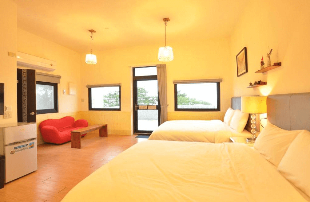 【長濱住宿】台東跑者之家民宿溫馨家庭房，配有兩張雙人床與紅色沙發，空間寬敞，設有落地窗與戶外陽台，自然光充足。