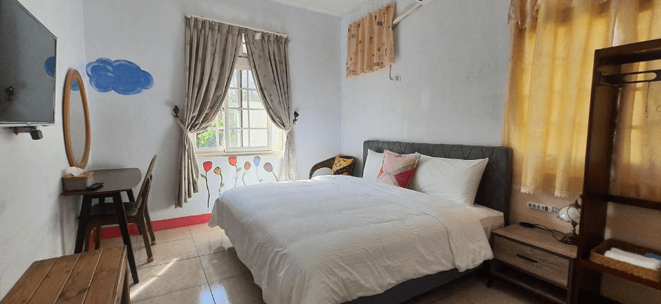 【長濱住宿】小阿姨野花雙人房，牆面彩繪可愛氣球與雲朵圖案，搭配簡約木質傢俱與白色寢具，營造溫馨童趣氛圍，窗外自然光充足。