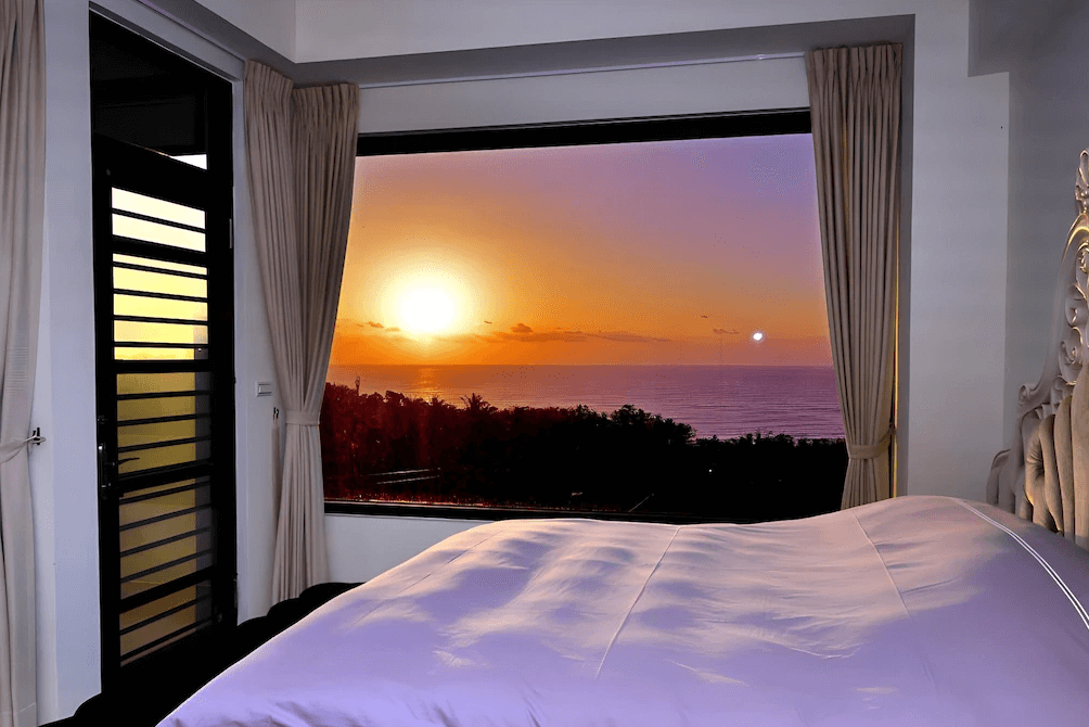 【台東成功住宿】"台東成功鎮住宿精選示意圖"台東「小馬日光涵館」海景雙人房內景，設有一張舒適雙人床，大片景觀窗外可欣賞壯麗的夕陽海景，金黃與紫紅交織的晚霞為房內增添浪漫氛圍。