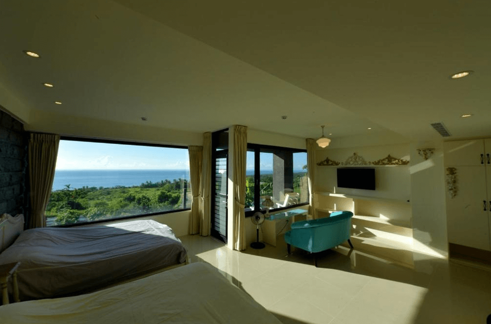 【台東成功住宿】台東「小馬日光涵館」家庭海景房空間寬敞，設有兩張雙人床、沙發與書桌，大面積玻璃窗提供遼闊海景與山景視野，採光極佳，整體空間優雅舒適。