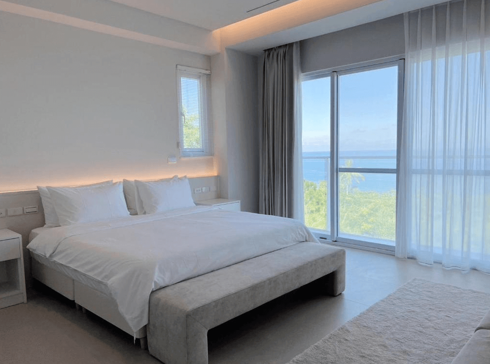 【東河住宿】川三白。秘境莊園海景雙人房，房間採極簡純白風格設計，配有大片落地窗，可遠眺蔚藍海景與綠意山林，床鋪潔白寬敞，空間安靜舒適，散發高級度假氛圍。