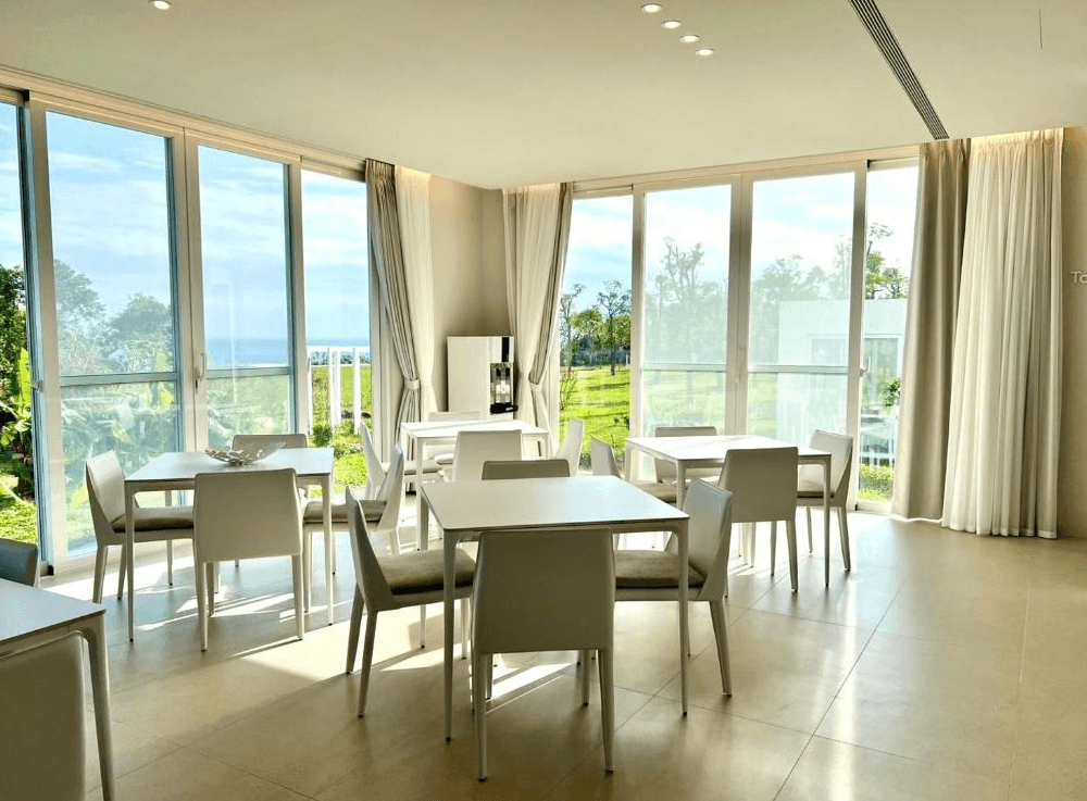 【東河住宿】川三白。秘境莊園公共用餐區，擁有大片玻璃帷幕與自然光，座位簡潔雅緻，可眺望戶外草地與遠方海景，是享用早餐或下午茶的絕佳場域。