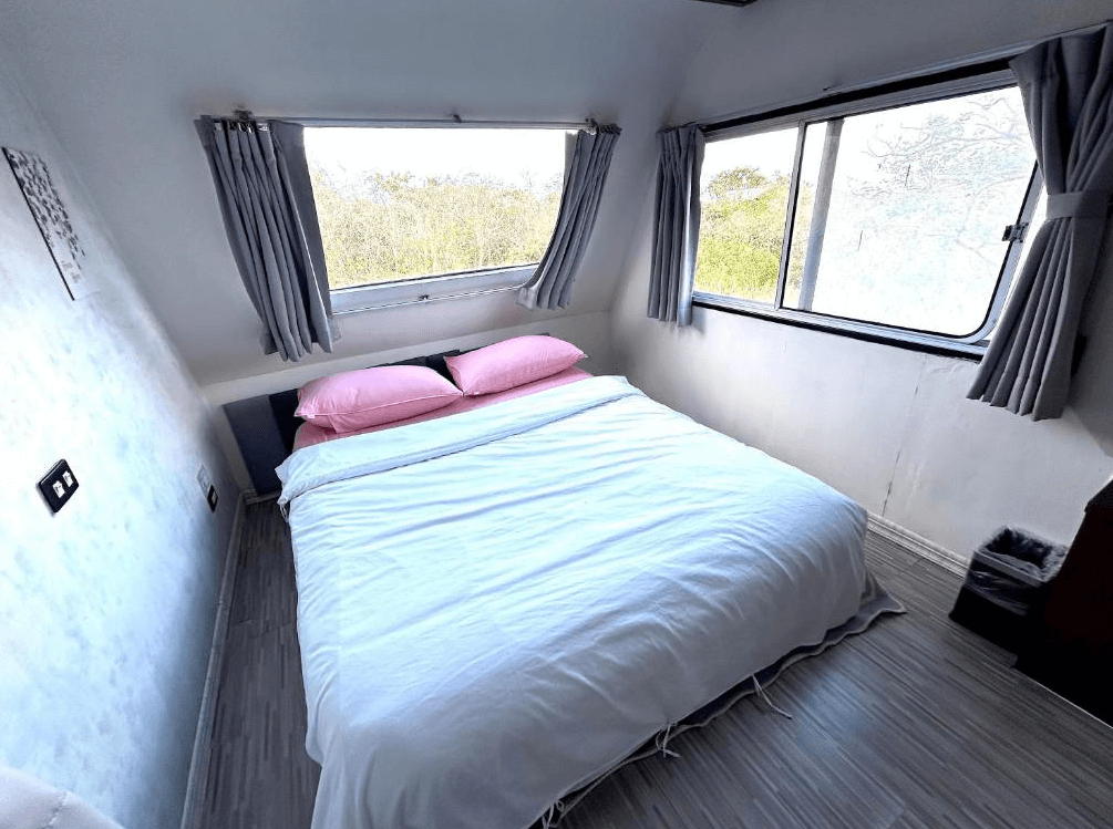 【台東成功住宿】台東「巴斯拉岸民宿」膠囊小屋風格房型，房內設有一張雙人床，空間雖小但舒適整潔，四周圍繞窗景，可享受寧靜綠意與獨立私密的住宿體驗。