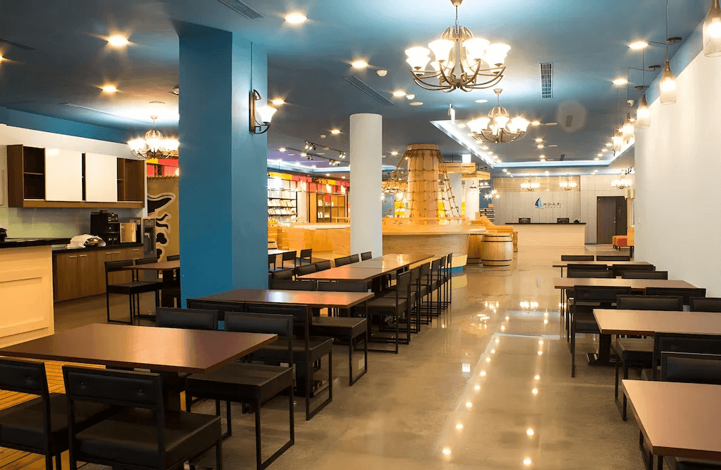 【布袋住宿】布袋文創HOTEL一樓大廳及用餐區，設計明亮寬敞，以藍白色調為主，搭配現代吊燈與木質裝飾，提供自助早餐與休憩空間，後方為接待櫃台。