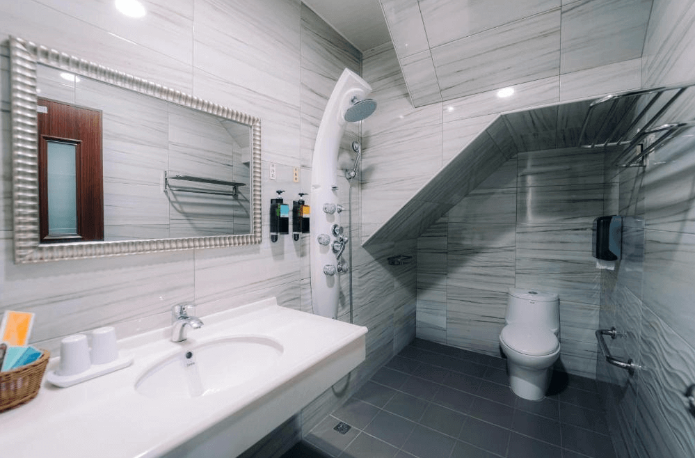 【玉井住宿】微風栩栩 & 晴意天空的浴室空間，設計明亮整潔，採用大理石紋牆面與灰色地磚，配備乾濕分離的淋浴設備與多功能花灑，另設有洗手台、大鏡子與洗手間，實用且清潔度佳。