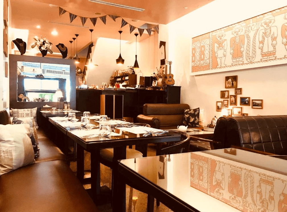 【玉井住宿】恩典之家民宿的用餐與公共空間，設計融合歐式與手作風格，皮革沙發與木質桌椅營造出溫馨居家感，牆上掛有原住民風格畫作與照片牆，空間佈置充滿個人特色。