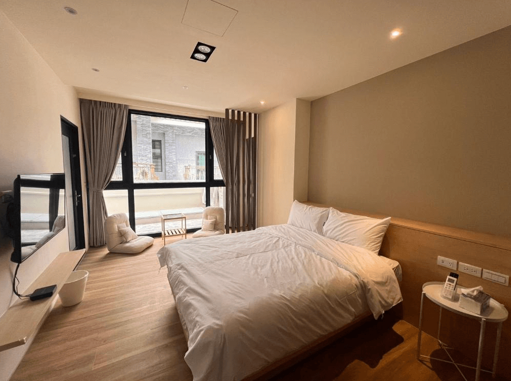 【關山住宿】懶得棟民宿的日系風格雙人房，木質地板與柔和色調營造溫潤質感，窗邊設有懶骨頭與小茶几，營造放鬆悠閒的住宿空間。