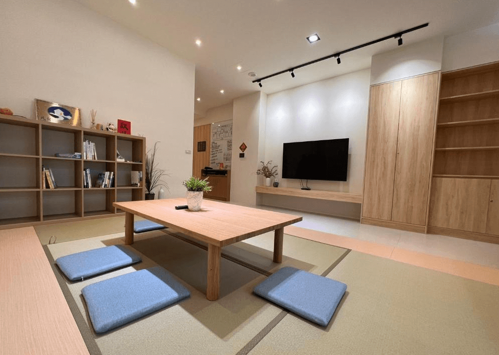 【關山住宿】懶得棟民宿的公共空間，設有日式榻榻米、矮桌與坐墊，搭配木製書櫃與電視牆，營造舒適溫馨的閱讀與休憩空間。