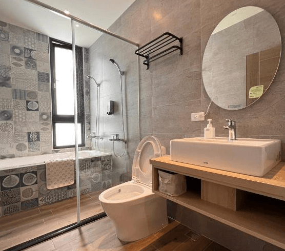 【關山住宿】懶得棟民宿的現代浴室，配備乾濕分離淋浴間與浴缸，牆面採花磚與灰色磁磚搭配，並設有圓鏡與簡約洗手台，整體清爽有設計感。