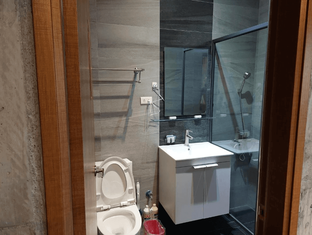 【玉井住宿】望明79民宿的現代簡約浴室，採用灰黑色系磁磚設計，設有乾濕分離淋浴間、洗手台與馬桶，空間整潔實用，牆上配有電吹風與毛巾架，提供完善的衛浴設備。