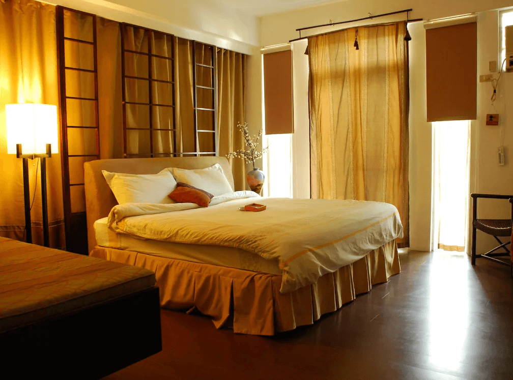 【苗栗包棟民宿】栗田庄民宿的客房採暖色系設計，融合日式禪風元素，搭配柔和燈光與拉門造型裝飾，營造靜謐舒適的休憩空間，窗簾柔和遮光，適合放鬆休息。