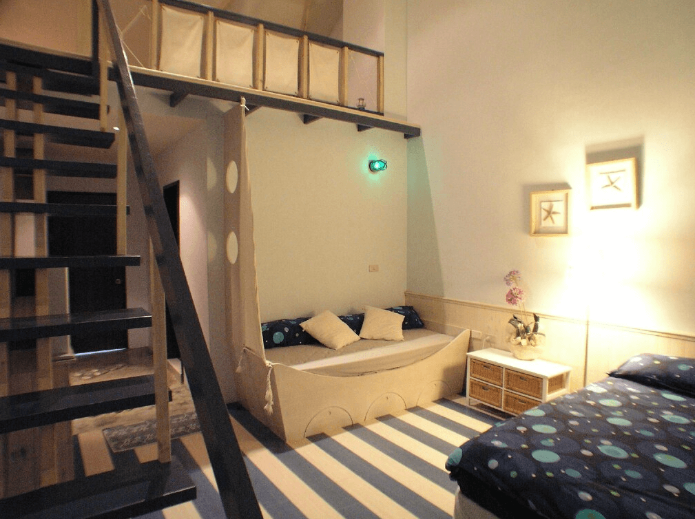 【苗栗包棟民宿】栗田庄民宿富童趣的樓中樓房型設計，設有小帳篷造型床舖與雙人床，樓梯通往上層閣樓空間，適合親子同樂與創造回憶。