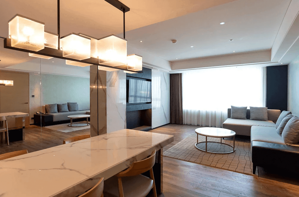 【桃園機場住宿】桃園喜來登酒店的高級套房客廳，設有寬敞沙發區、圓形茶几與大理石餐桌，吊燈設計現代典雅，空間寬敞舒適。