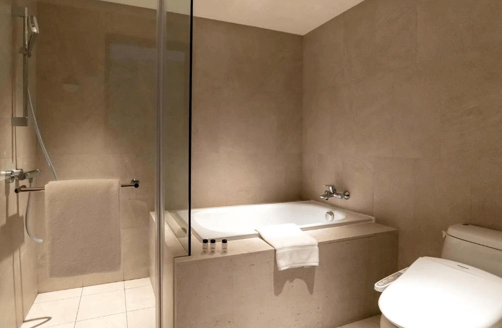 【桃園機場住宿】桃園喜來登酒店的現代化浴室，配備獨立淋浴間、浴缸與免治馬桶，整體以米色系磁磚打造簡潔高雅的空間設計。