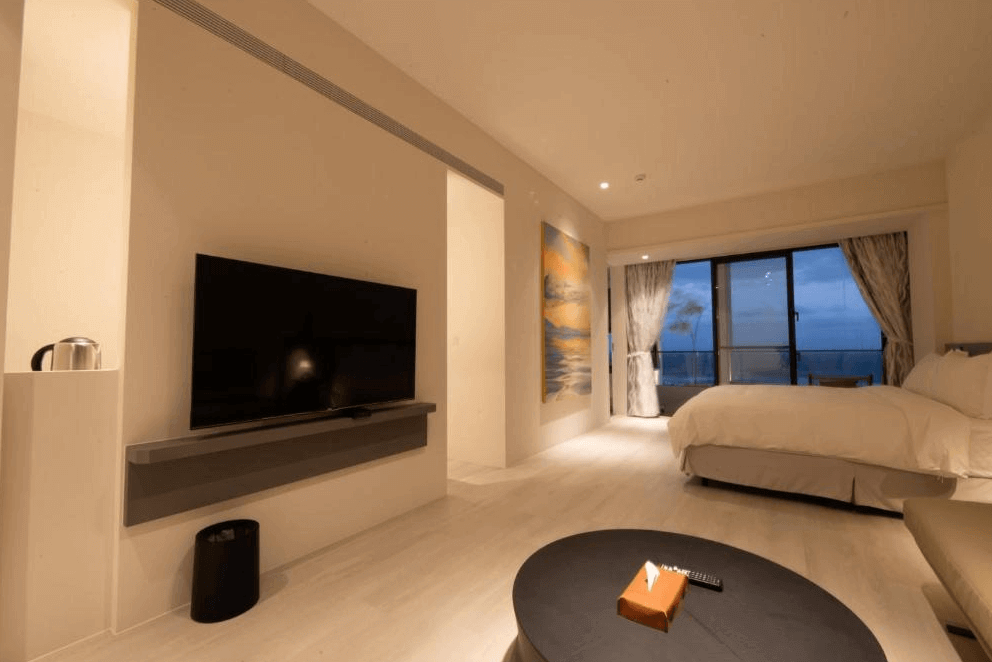 【豐濱住宿】夜晚的水樹 AQUATREE RESORT 海景套房展現靜謐氛圍，大片落地窗前可觀賞夜色中的海岸線，房內配置大尺寸電視與沙發區，搭配低調燈光設計，適合放鬆心情享受靜夜。