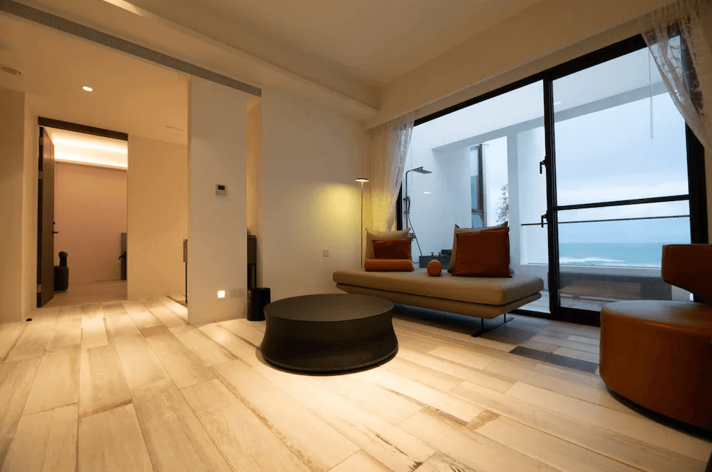 【豐濱住宿】水樹 AQUATREE RESORT 的套房客廳設計現代時尚，設有舒適沙發與簡約茶几，玻璃門外即是陽台與海景，空間通透明亮，是品茶聊天或觀海放空的理想角落。