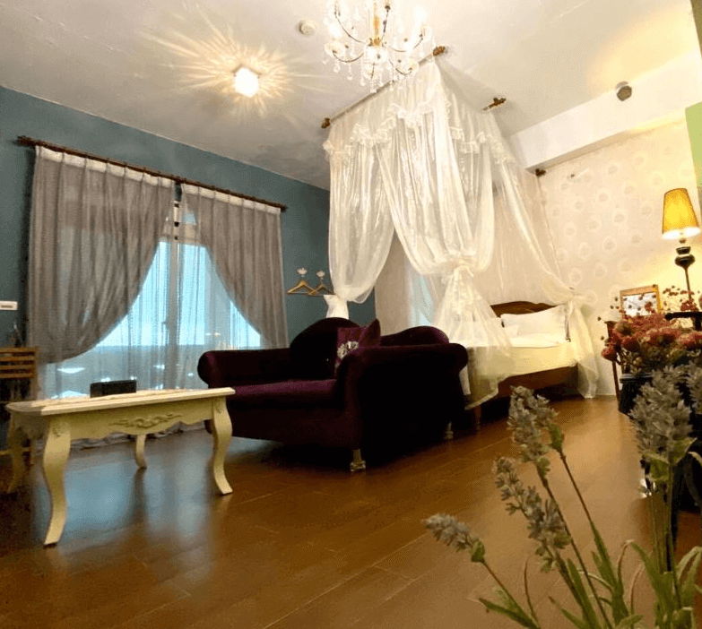 【豐濱住宿】海公主民宿的浪漫雙人房以白紗天幕與水晶吊燈打造童話氛圍，房內設有酒紅色絨布沙發與鄉村風家具，窗外透進自然光，空間溫馨典雅，適合情侶度假入住。