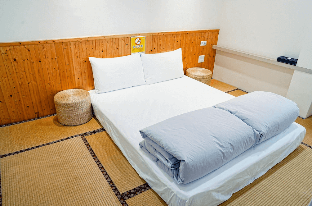 【布袋住宿】海風長堤民宿二館日式榻榻米雙人房，床墊鋪設於榻榻米地板上，搭配木質牆板與編織坐墊，營造出溫馨簡約的和風氛圍，適合喜愛日式風格的旅客。