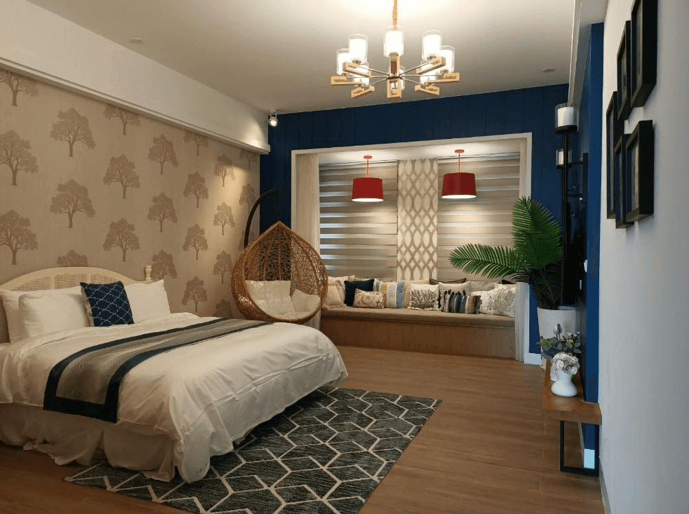 【玉井住宿】瓦樣山巷的寬敞雙人房，主牆以樹影圖樣壁紙妝點，床鋪潔白柔軟，搭配深藍色系抱枕與床旗。房內設有吊椅與大片窗邊座位區，紅色吊燈與深藍主牆形成強烈對比，整體設計兼具舒適與時尚感。