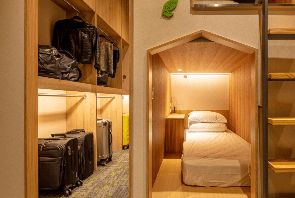 【桃園機場住宿】町草休行館的單人膠囊床位，附有收納櫃與衣物掛架，行李置放空間充足，整體風格簡約而溫馨。