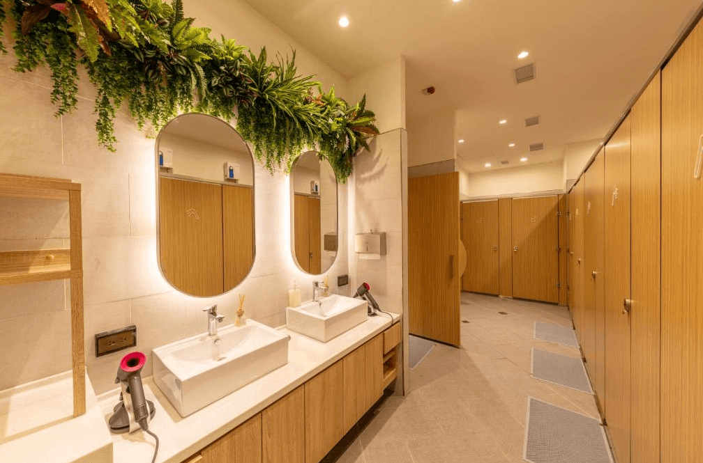 【桃園機場住宿】町草休行館的共用衛浴空間，配置有雙洗手台與梳妝區，牆面綠植點綴設計清新，盥洗間寬敞明亮。