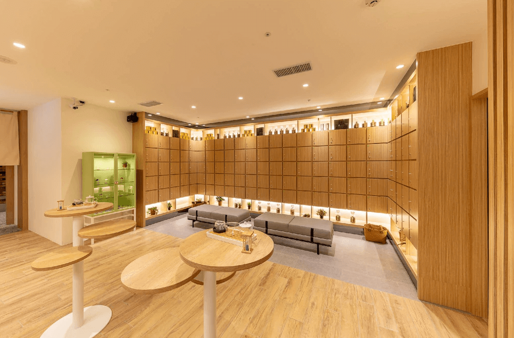 【桃園機場住宿】町草休行館的公共交誼廳與置物櫃區，採用大量木質元素營造溫暖氛圍，設有高腳桌、展示櫃與舒適座椅，適合旅客放鬆交流。