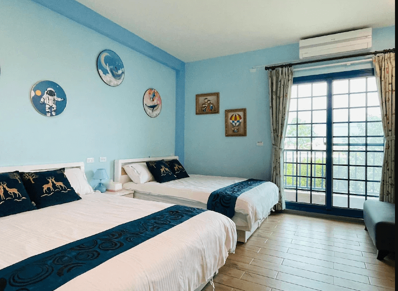 【關山住宿】稻香田園民宿的親子四人房，以天藍色牆面搭配可愛太空與動物圖案裝飾，配置兩張雙人床，充滿童趣與清新氣息。
