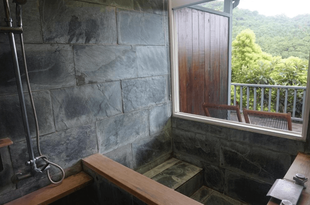 【長濱住宿】竹湖山居民宿石材浴池設於室內空間，附設窗景可觀賞戶外綠林與陽台休憩椅，是放鬆泡湯的理想空間。