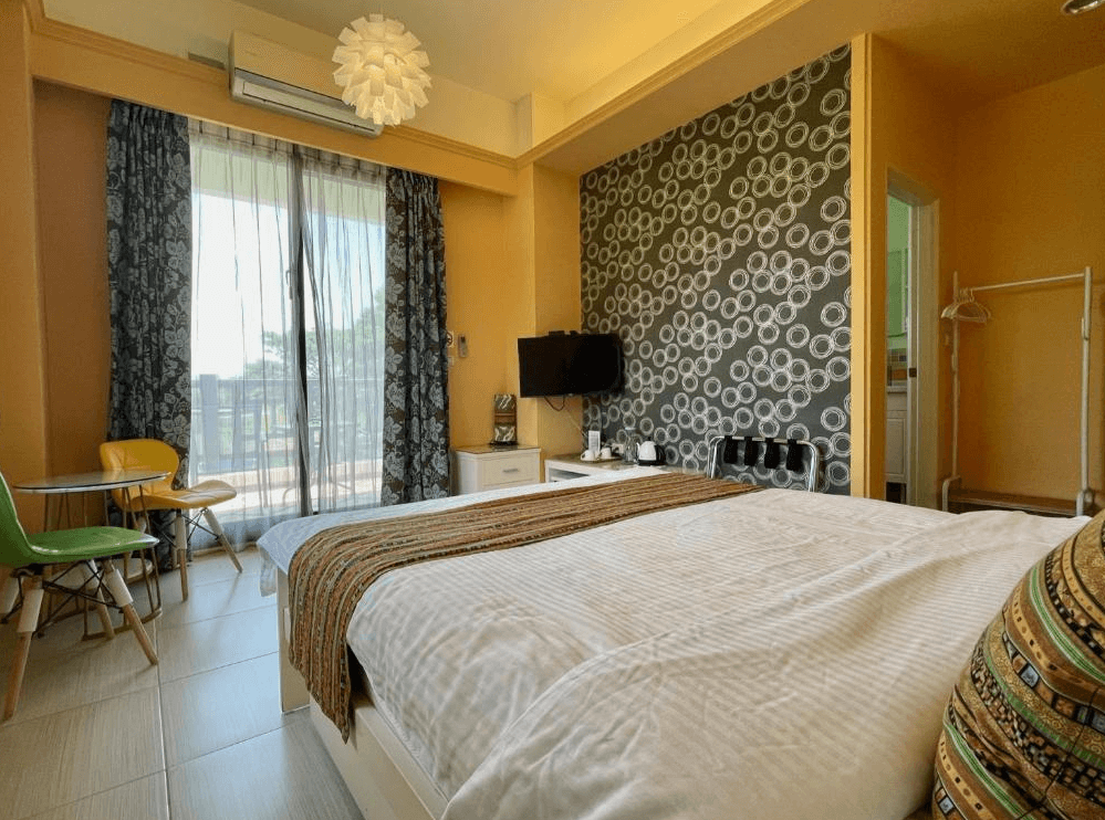 【關山住宿】纏民宿 x Remindful 的現代感雙人房，牆面以橘色與黑白圓圈花紋裝飾，陽台外景致遼闊，適合享受靜謐早晨。