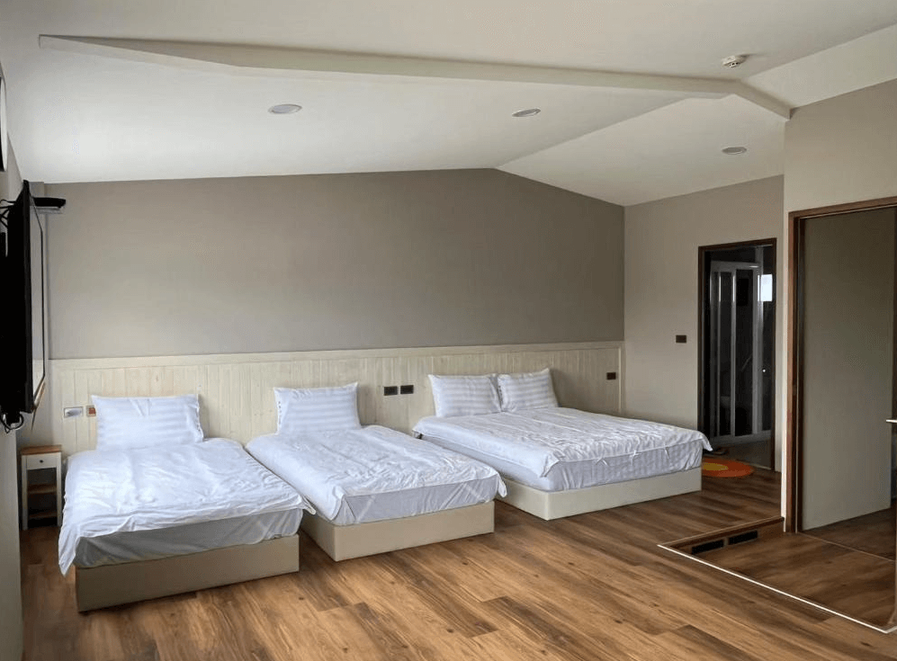 【關山住宿】興源行民宿的三人房空間，擁有兩張單人床與一張雙人床，房內設計簡約清爽，木地板搭配米灰色牆面，整體乾淨明亮。